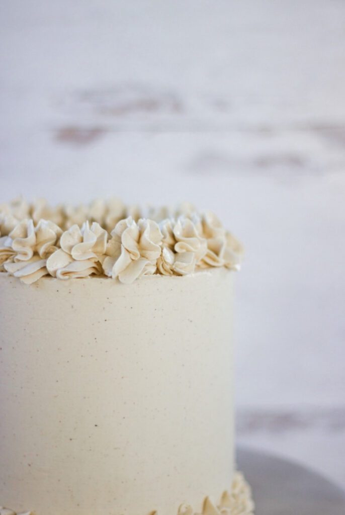 Chai Cake with white frosting and a white wood background.