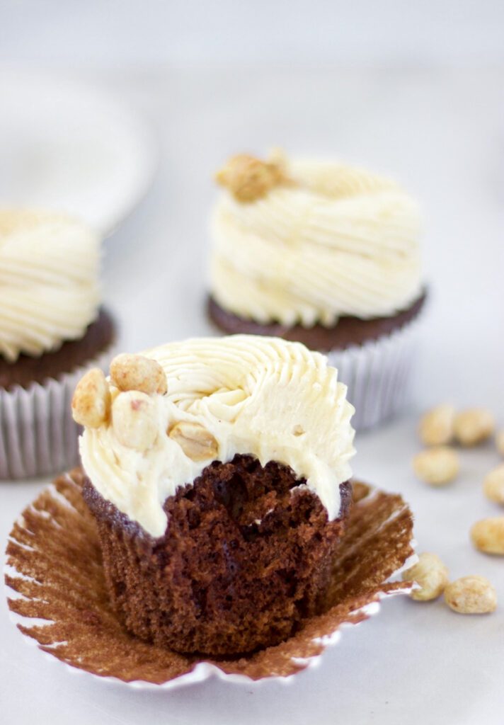 Peanut Butter Chocolate Cupcake out of wrapper with a bite taken out on a white background.