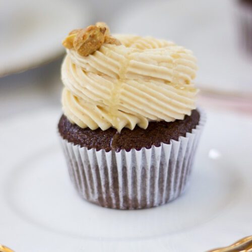 Decadent peanut butter chocolate cupcake on a plate, with buttercream frosting on top.