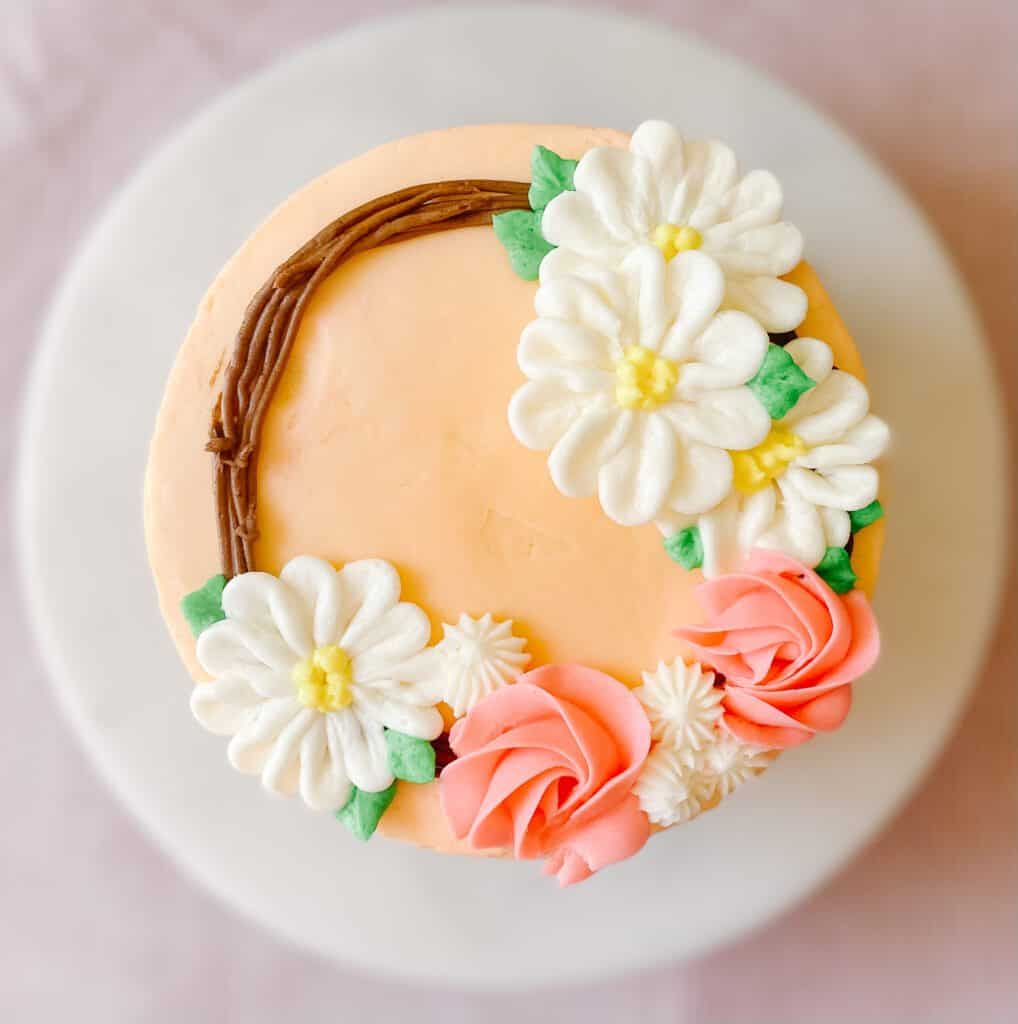 American Buttercream Frosting was used to decorate this cake, which has frosted daisies, roses, and puffs.
