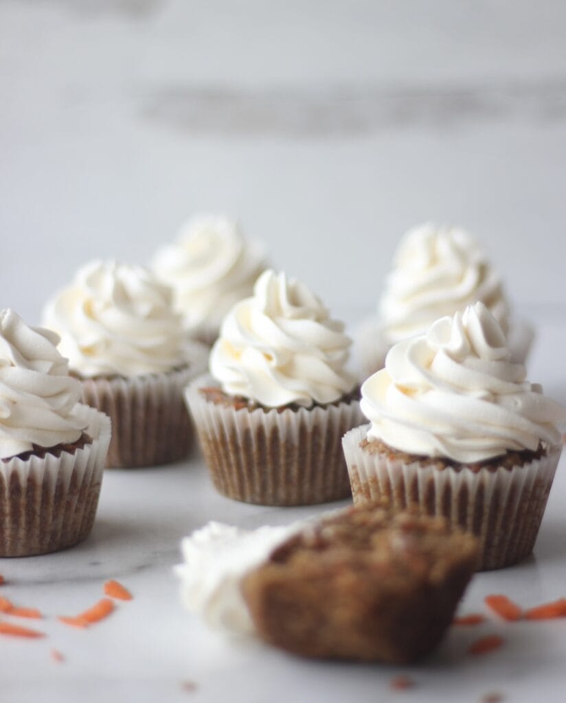 a group of carrot cupcakes frosted sitting on the table