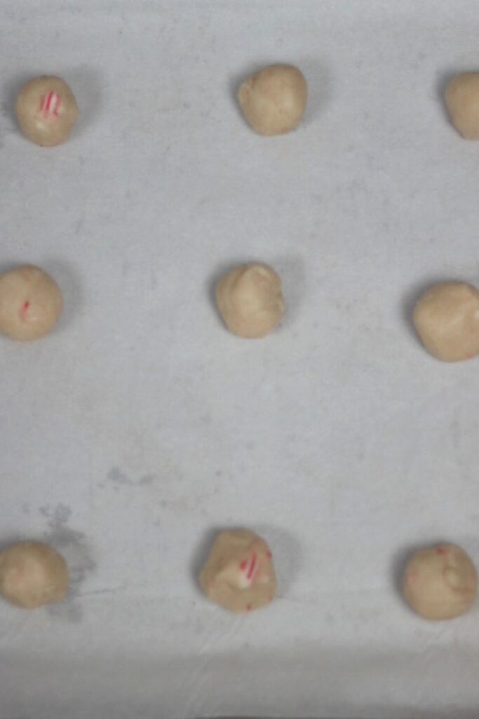 cookie dough on a cookie sheet rolled in balls