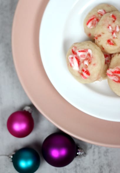 candy cane shortbread cookies on a plate with decorations beside them