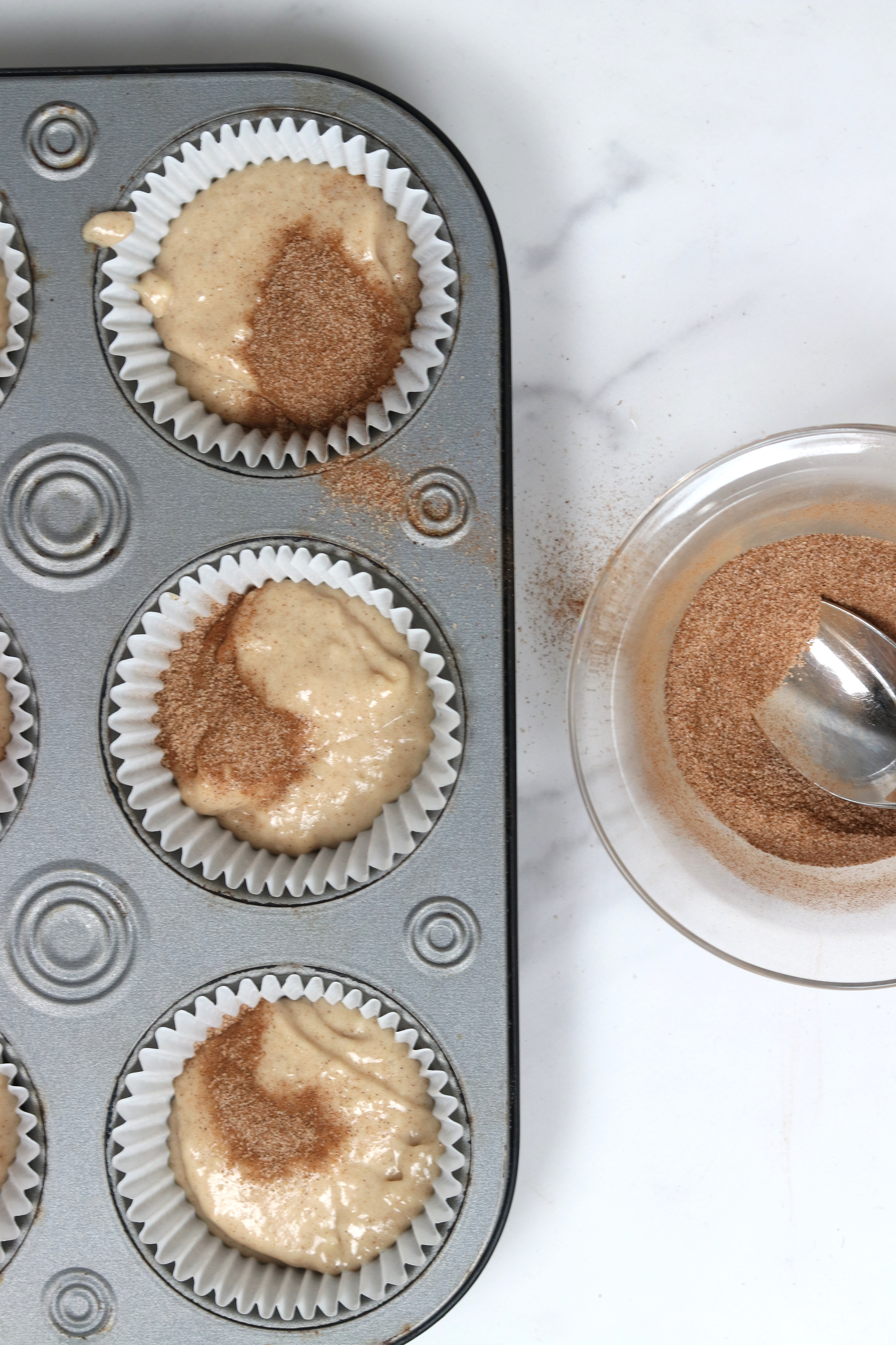 cupcake batter in tin with cinnamon on top