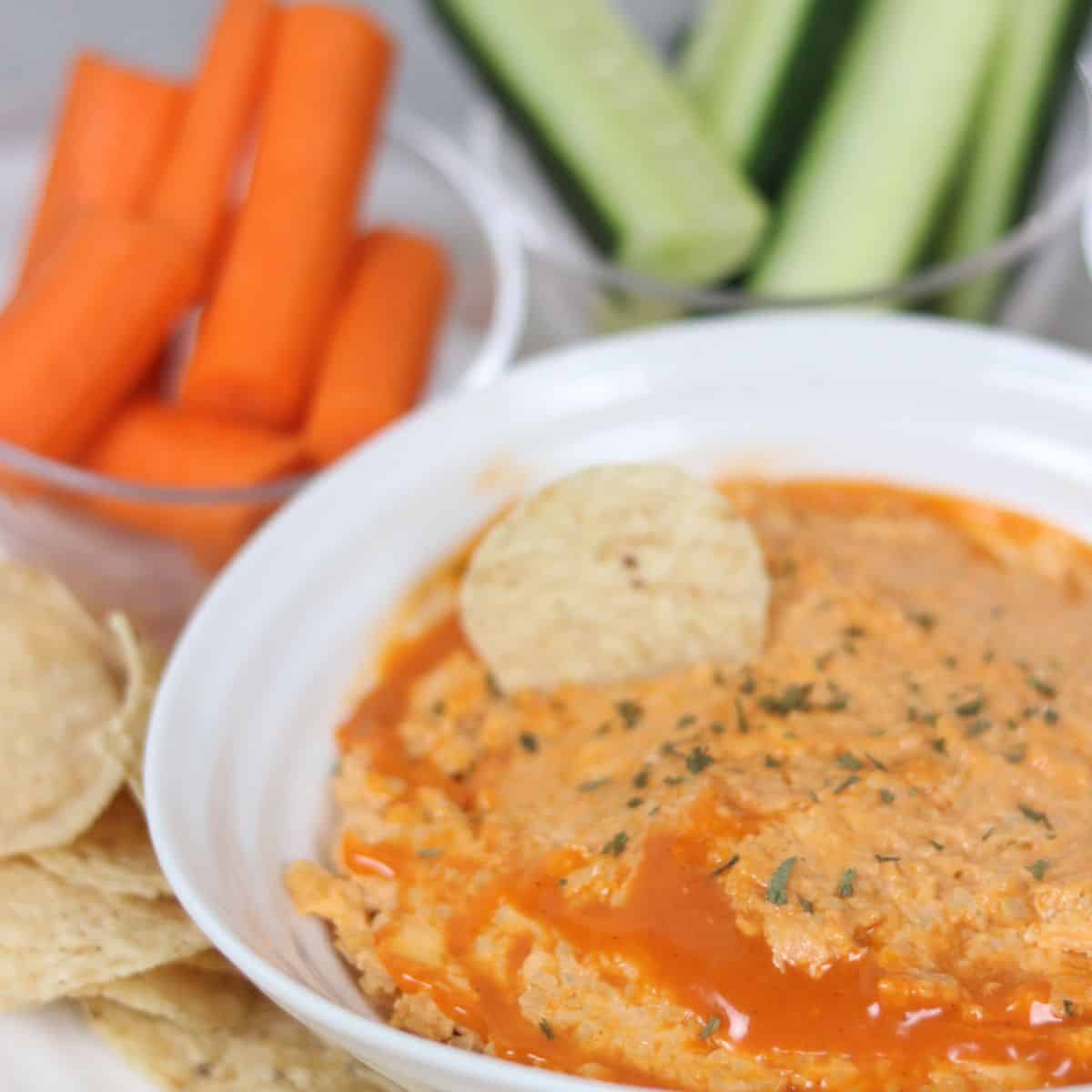 buffalo chickpea dip in a bowl with vegetables around it