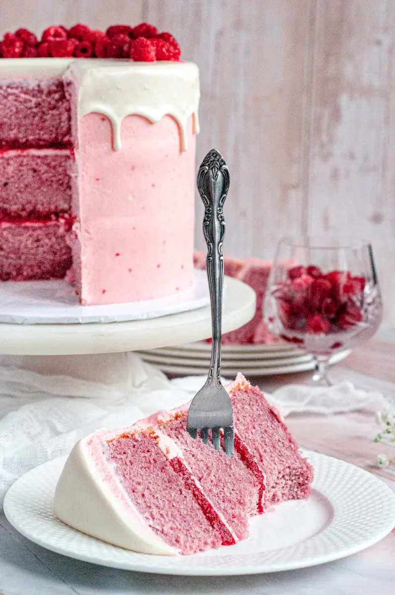 a slice of gluten free raspberry cake on a plate with a fork in it