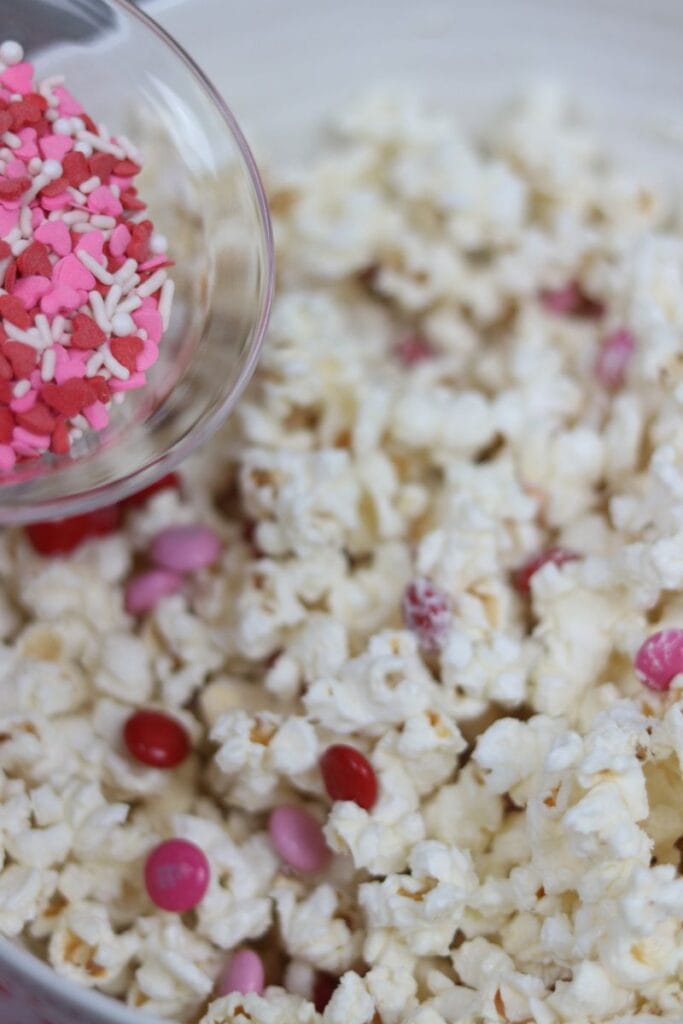 pouring sprinkles on valentines popcorn