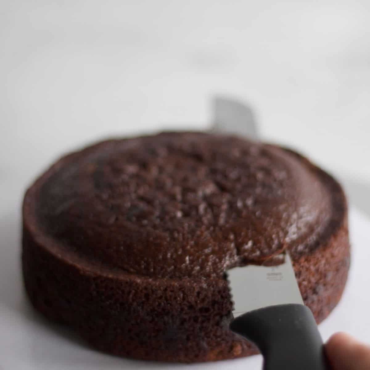 a chocolate cake layer top being cut with a knife