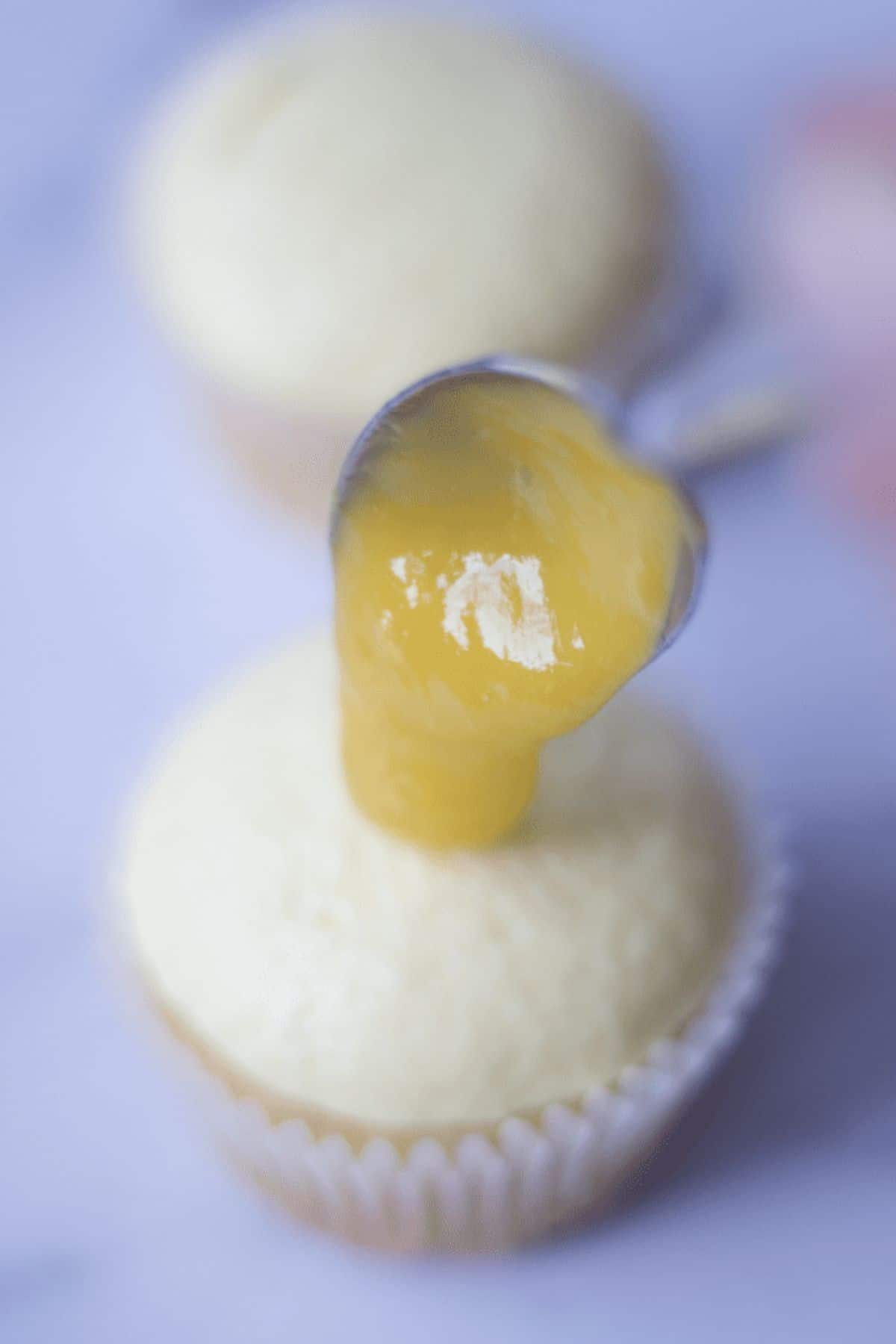 spooning mango puree on top of the mango cupcakes