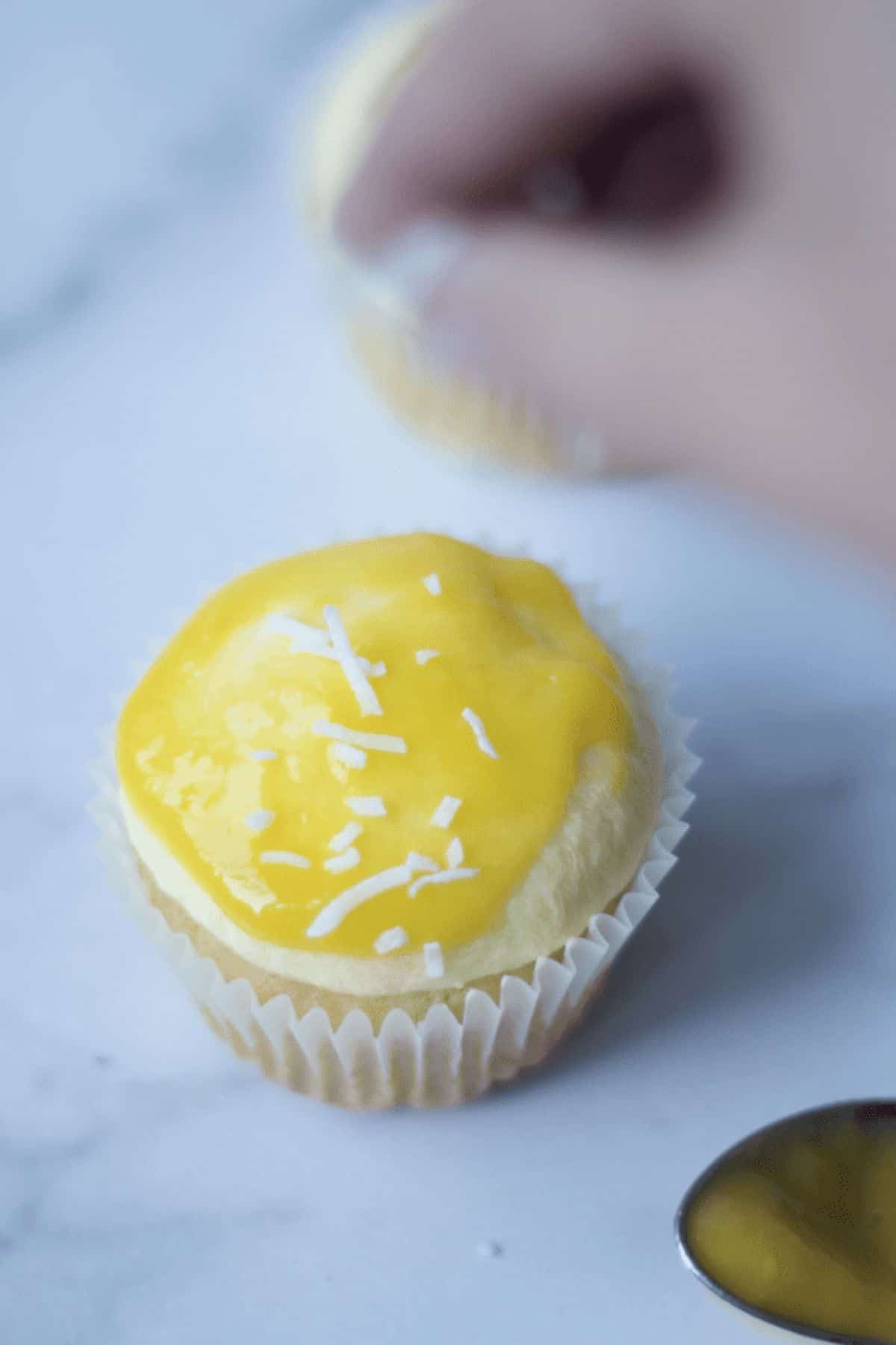 sprinkling coconut on the mango cupcakes